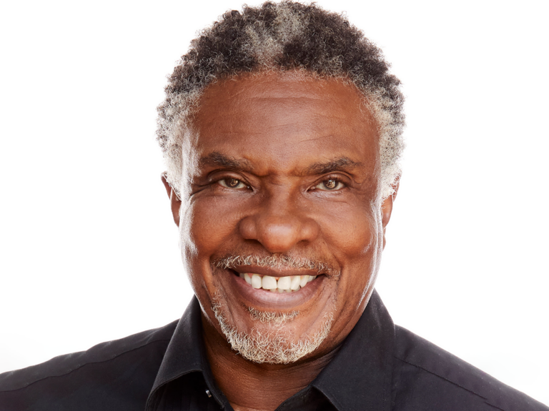 Keith David in a black shirt smiling.