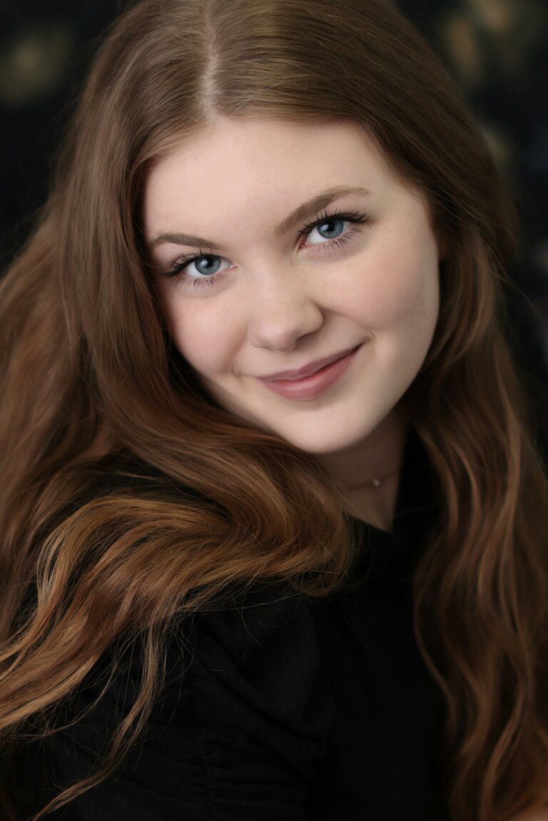 Kristen Duff smiling in front of a black background.