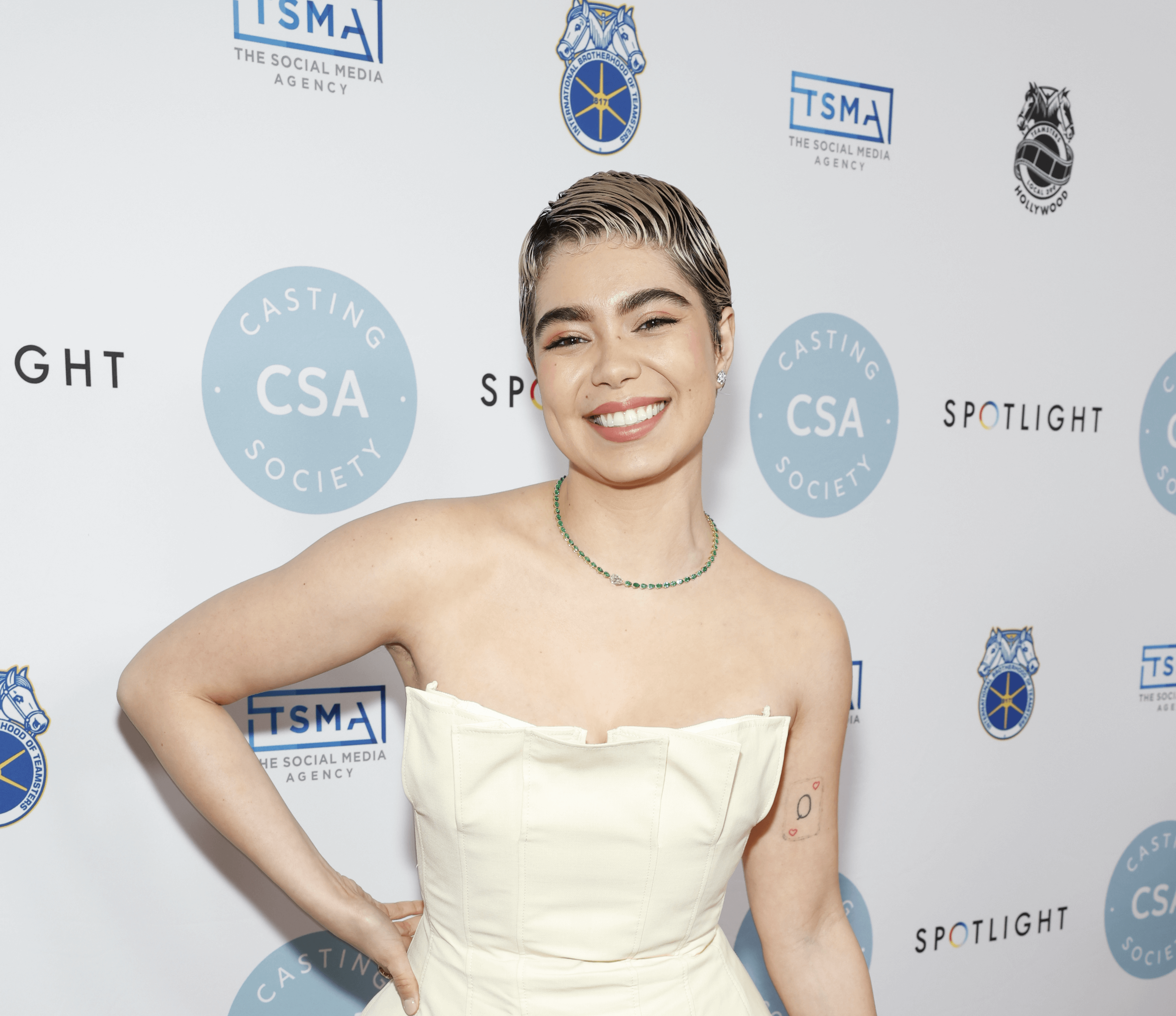 Auli'i Cravalho smiling in a white dress.