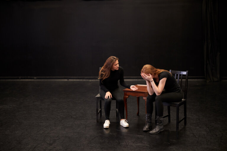 Two female acting students rehearsing onstage. One is upset.