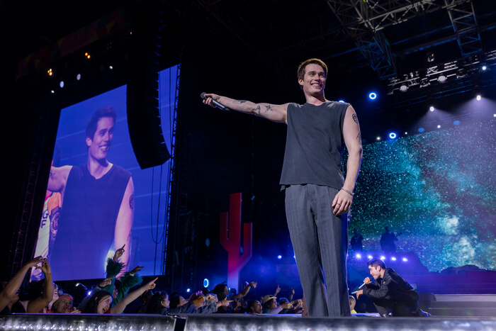 Nicholas Galitzine on stage at a concert pointing to the audience.