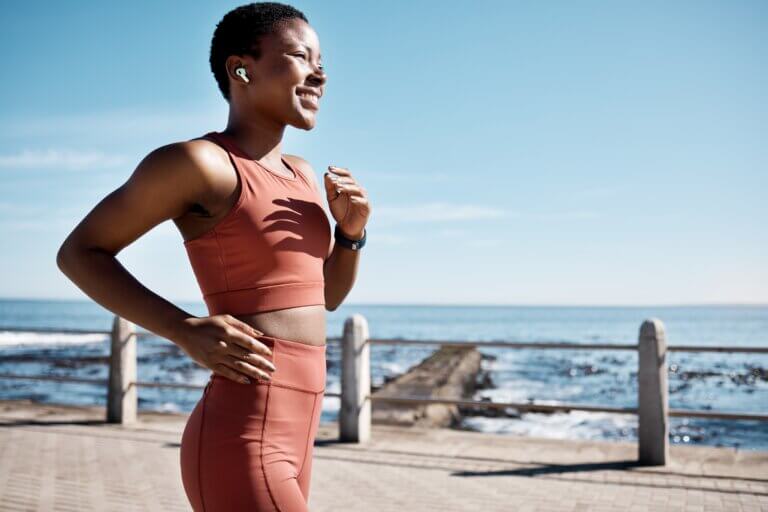 Happy black woman running on the pier on a sunny day.