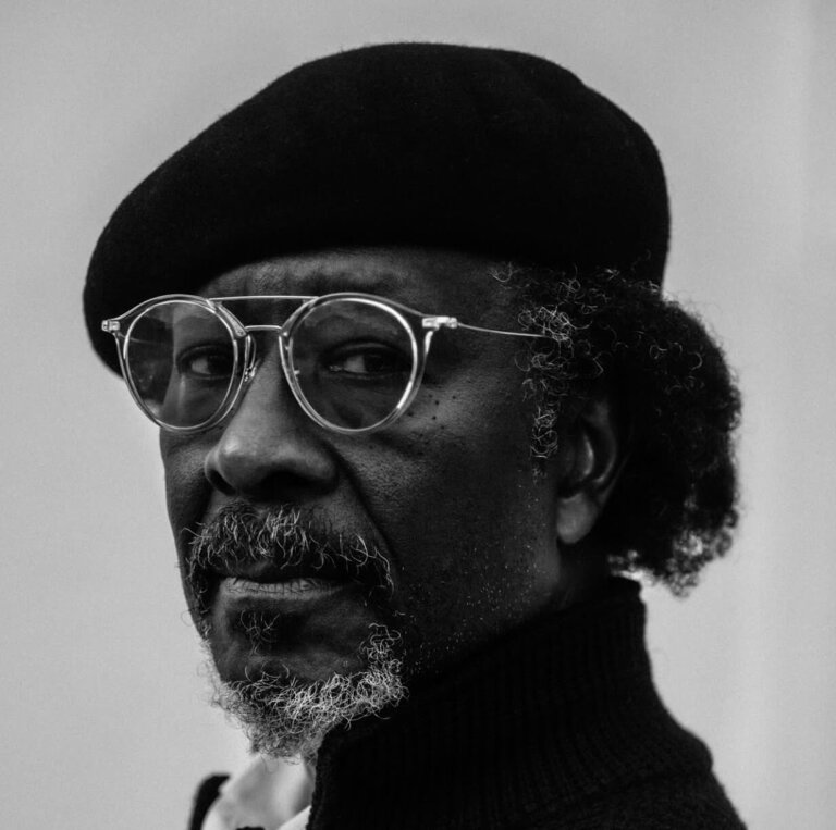 Clarke Peters in a Kangol hat looking stoic from the side.
