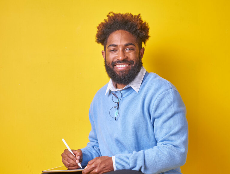 Koren Rolle sitting on a stool smiling.