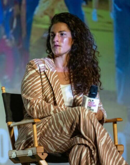Lindsay Weissmuller sitting in a director's chair wearing tiger print suit and talking on a panel.
