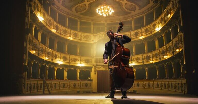 Male cellist playing the cello alone in an empty classic theatre.