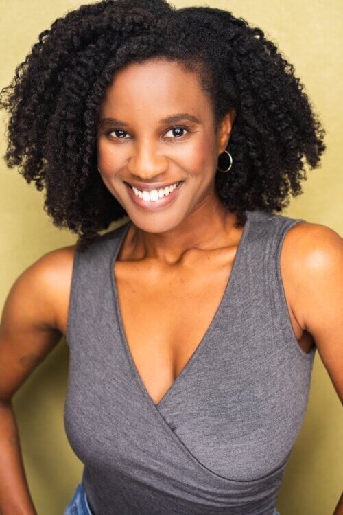 Tai Brown smiling in a sleeveless gray shirt.
