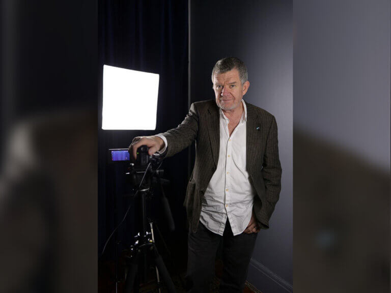 Casting Director Gregory Apps standing next to a camera.