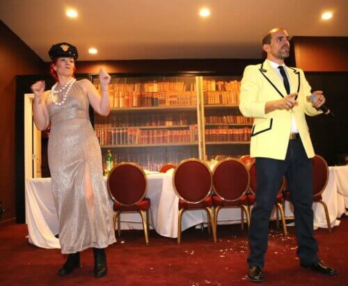 Christina Largent dancing in a dress and cop hat with a friend in a tuxedo.