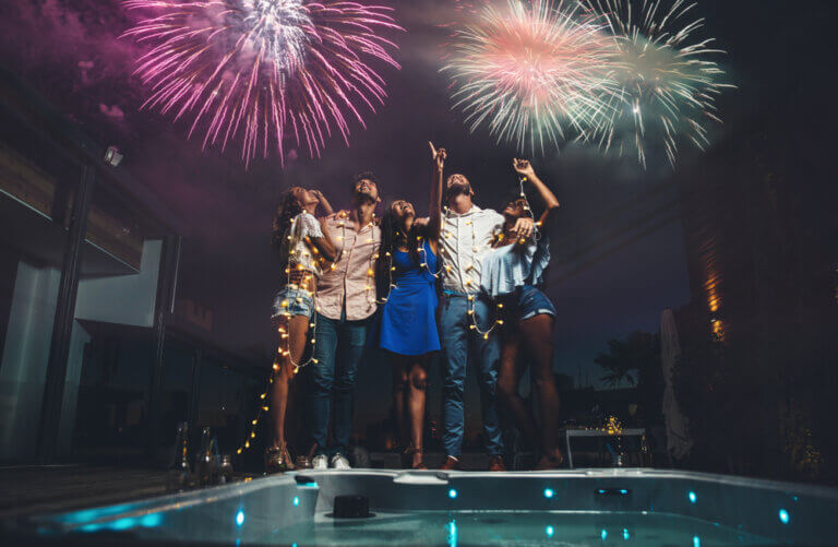 Diverse group of friends hanging out on 4th of July watching fireworks by the pool.