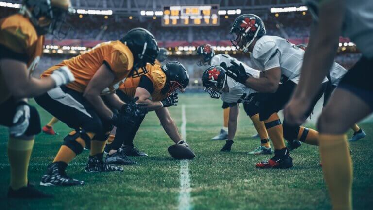 Two football teams about to start playing a game in a stadium.