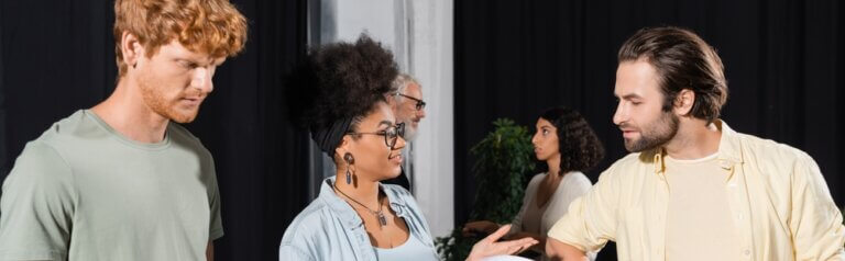 Two actors talking as another one waits to chat.