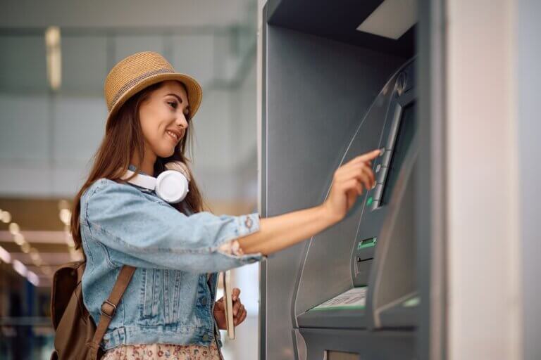 Happy Asian woman withdrawing money from the ATM.