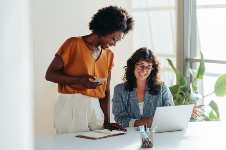 Two professional women chatting at work.