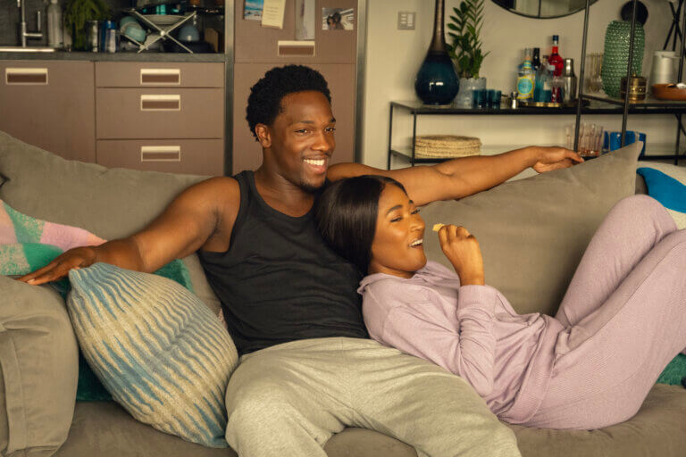 A Black couple sitting on the couch enjoying quality time together.