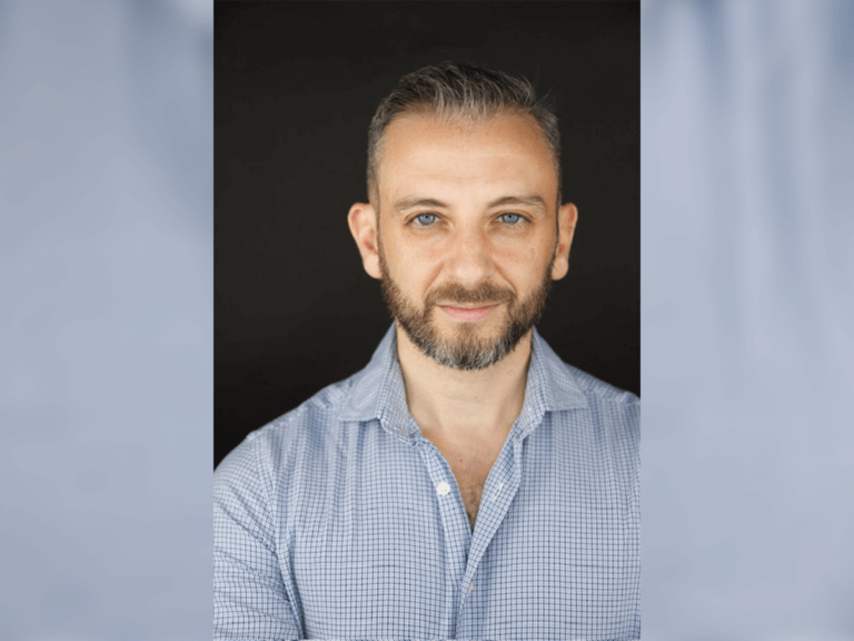 Armando Pizzuti smiling in a blue buttoned down shirt.
