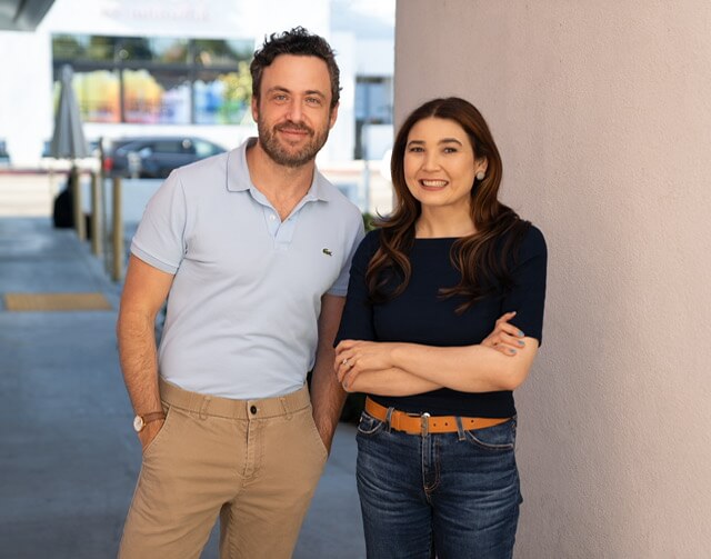 Castign Directors David Rapaport and Lyndsey Baldasare smiling in a parking lot.