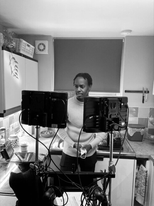 Joshua Okpala watching multiple monitors in a kitchen area.
