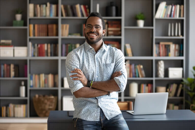 Happy and confident Black man in his home office surrounded by books.