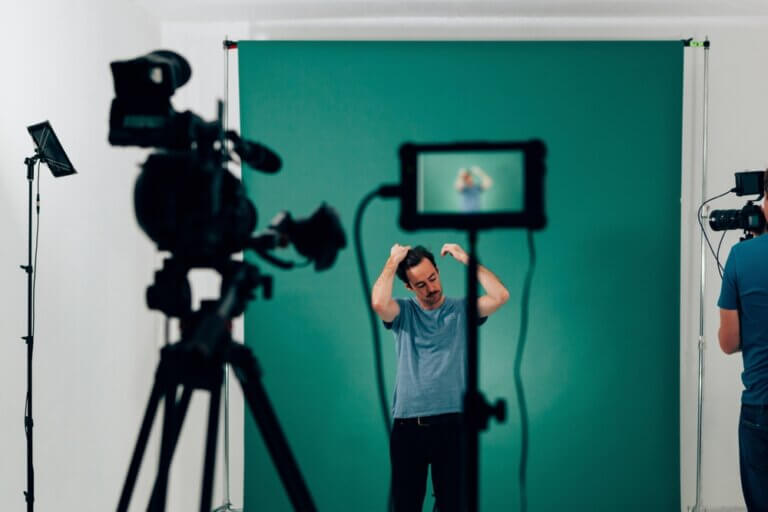 Actor recording a self tape commercial audition with cameras and a green backdrop.