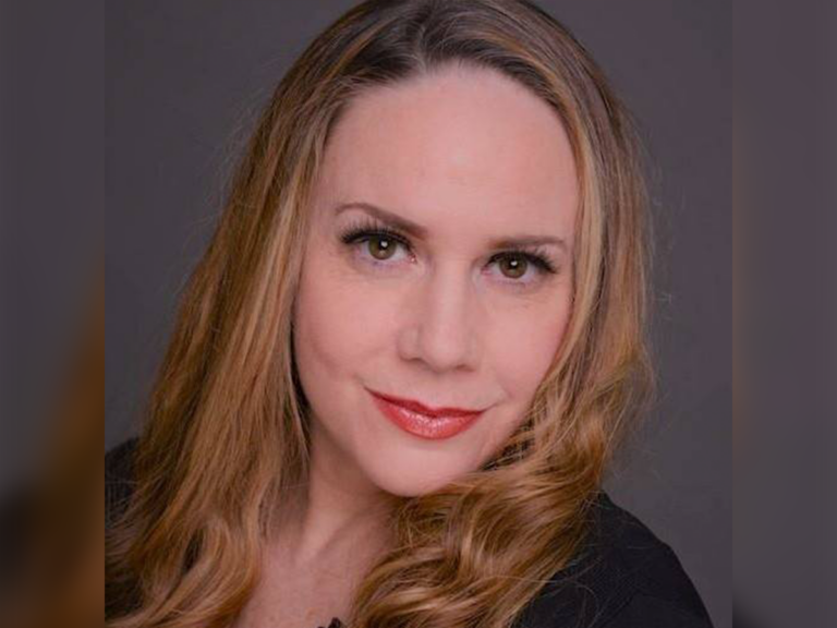 Casting Director Helene Rousse smiling in front of a gray background.
