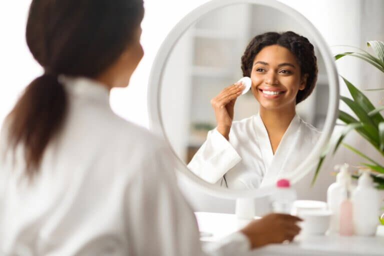 Young Black actress doing her skincare routine in front of a mirror before a shoot.