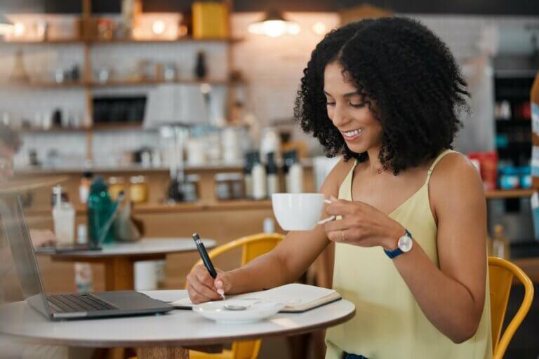 Young biracial woman on her laptop writing notes in a coffee shop.