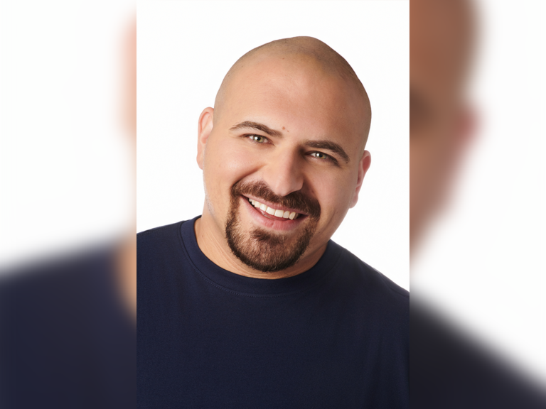 Actor Greg Hoffman smiling in a black shirt.