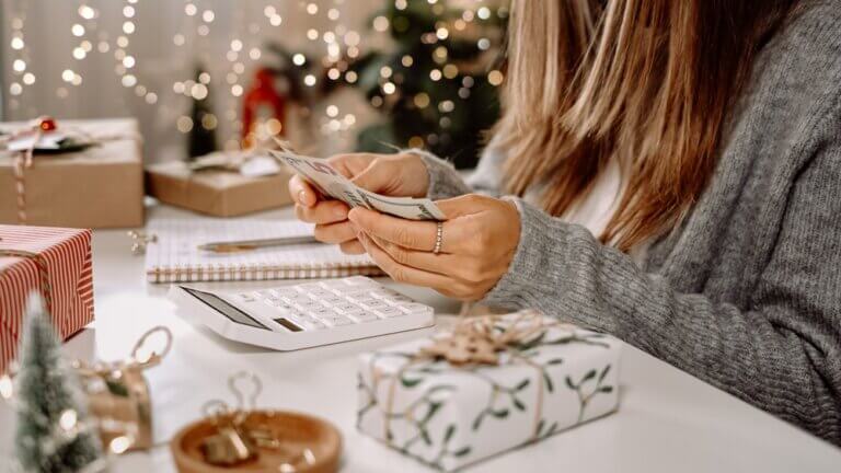 Young woman doing financial planning and counting dollar bills during the holidays.