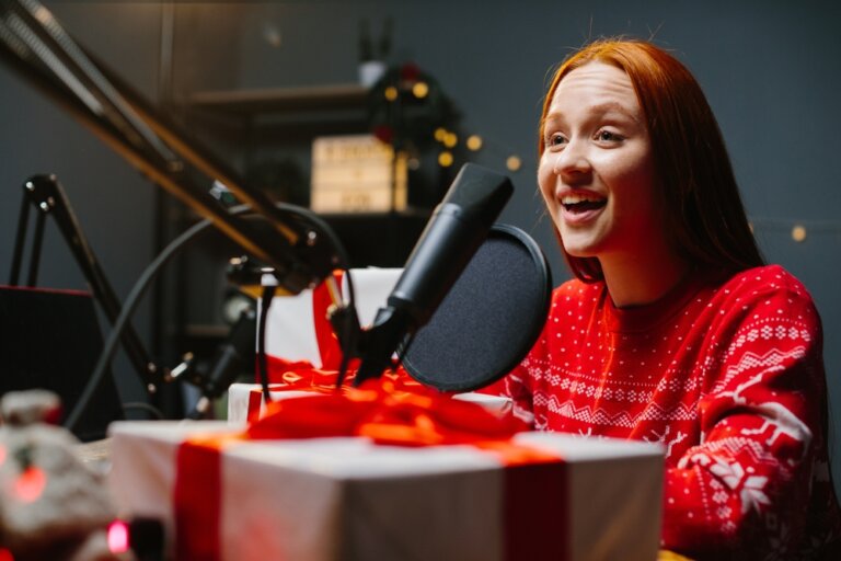Female voice actor performing a holiday themed voiceover spot at a desk with a present.