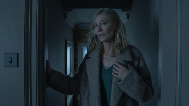 Cate Blanchett as Catherine Ravenscroft looking concerned and wearing a winter jacket inside.