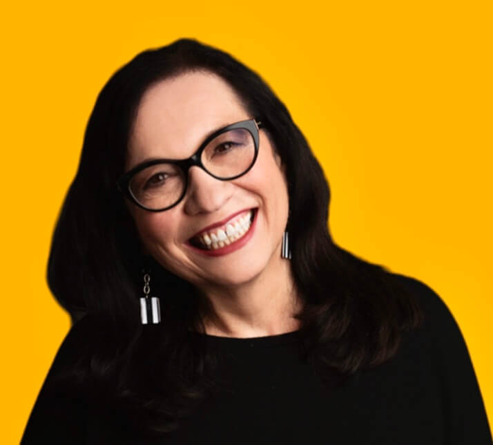 Casting Director Rose Rosen smiling in front of an orange background.