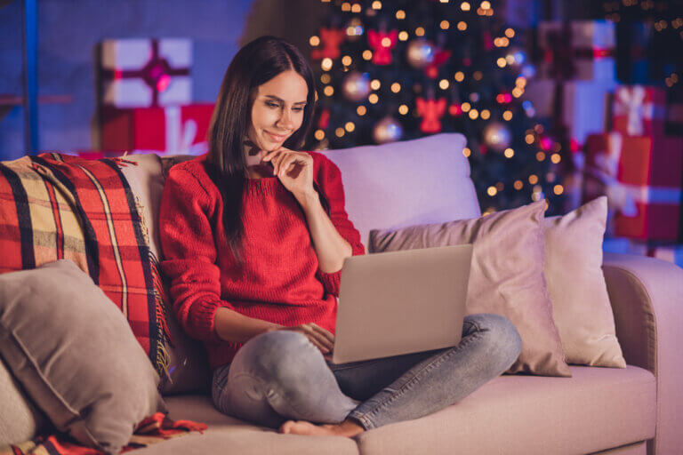 Casting director sitting on the couch at Christmas on her laptop.