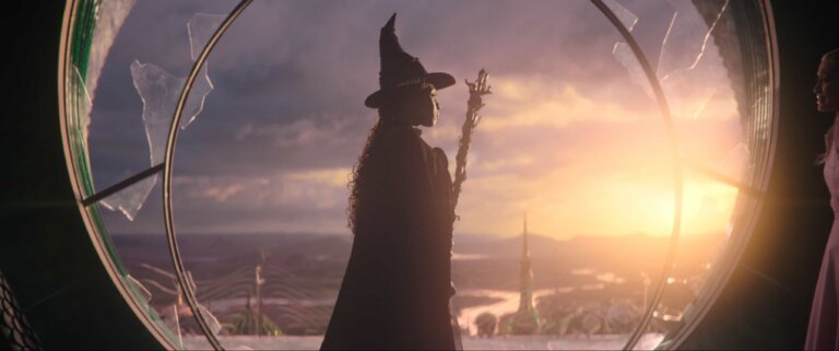 Wicked witch holding her broom overlooking the horizon of Oz.