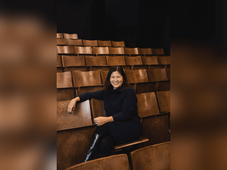 Cassandra Han sitting in an empty theater row smiling.