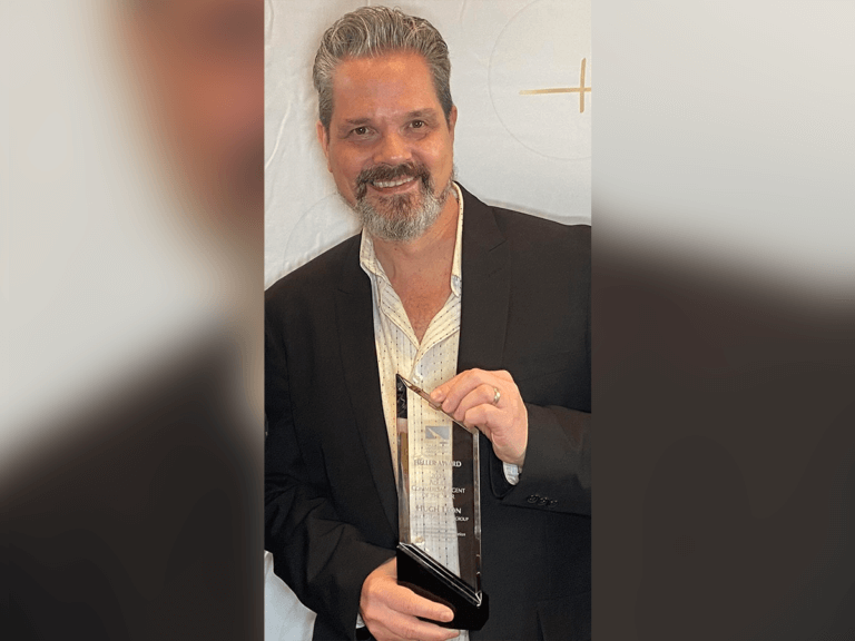 Talent Agent Hugh Leon holding a Heller award and smiling.