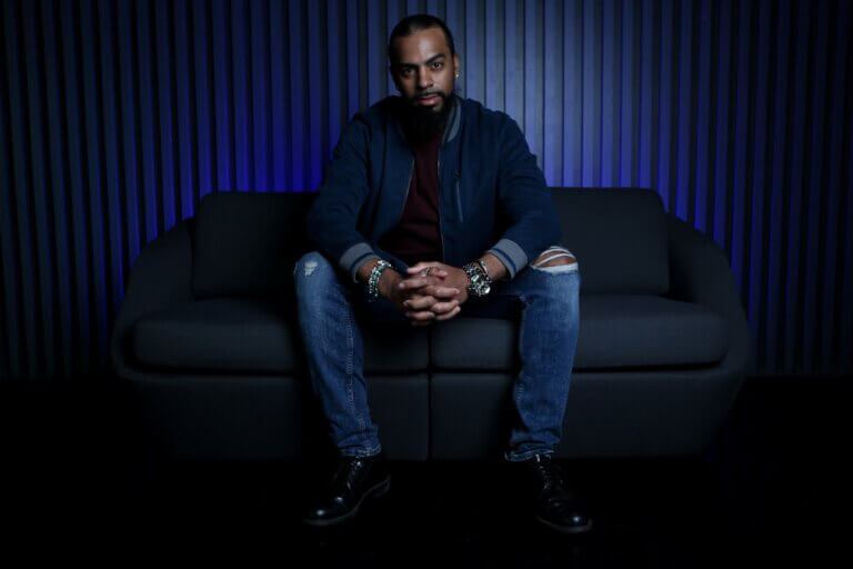 Matthew Horn looking cool in a blue shirt on a couch inside a nightclub setting.
