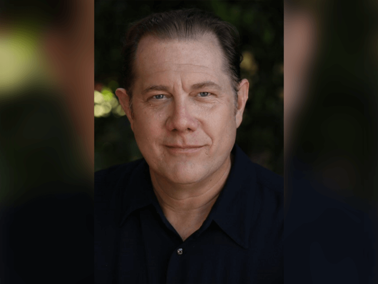 Voice actor Fred Tatasciore smiling outside in a blue polo.