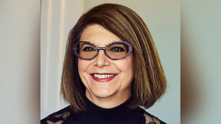 Casting Director Margery Simkin smiling in a nice black dress inside.