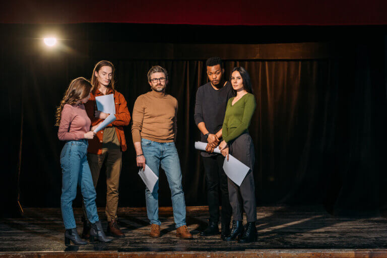 Diverse group of actors holding scripts waiting in an audition room.