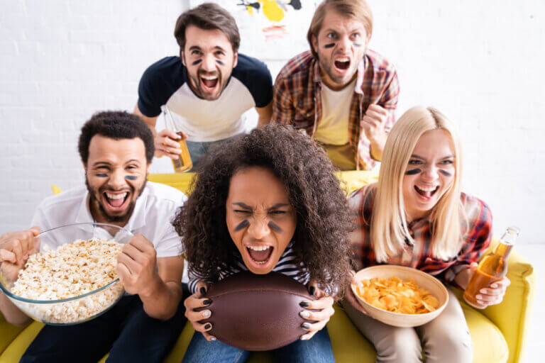 Diverse group of football fans watching the big game on the couch.