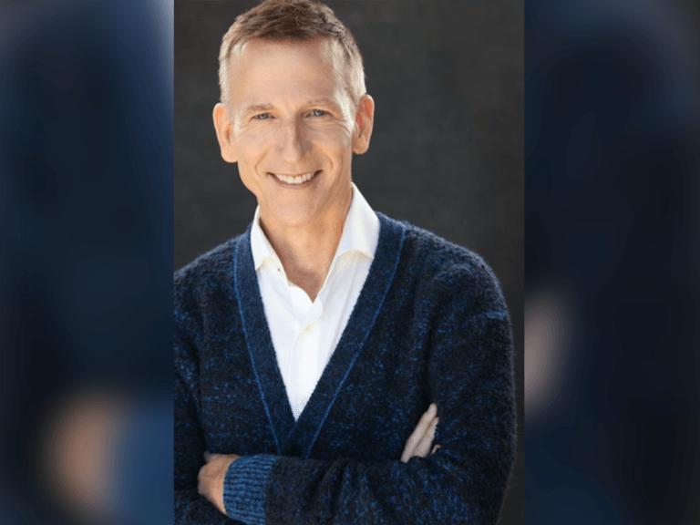 Casting Director Richard Hicks in a blue sweater with a white shirt smiling proud.