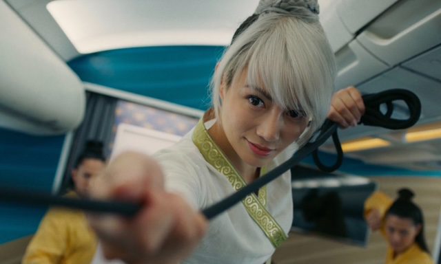 Juju Chan Szeto in a martial arts pose wearing traidtional fighting gear on a plane, ready to do battle.