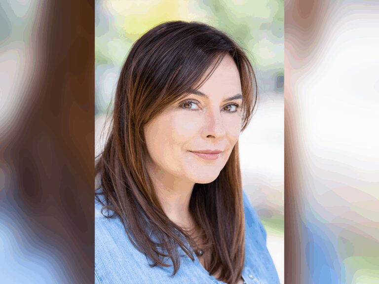 Casting Director Thea McLeod smiling outside in a blue shirt.