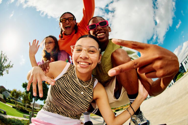 Diverse Gen Z group of friends hanging out in the summer time at a park.