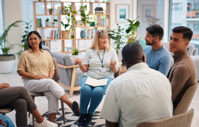 Diverse group of people in a support group talking and listening to others while giving advice on how to cope with life's challenges.