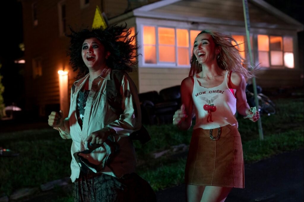Chloe Fineman and Sam Morelos running at night in a suburban neighborhood laughing and smiling.