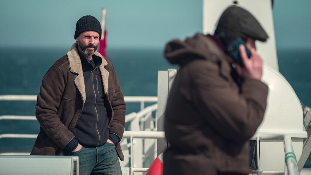 Matthew Goode on a boart outside investigating a crime in the show 'Dept. Q.'