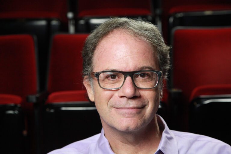 Casting Director Doug las Aibel sitting in an empty theater smiling.