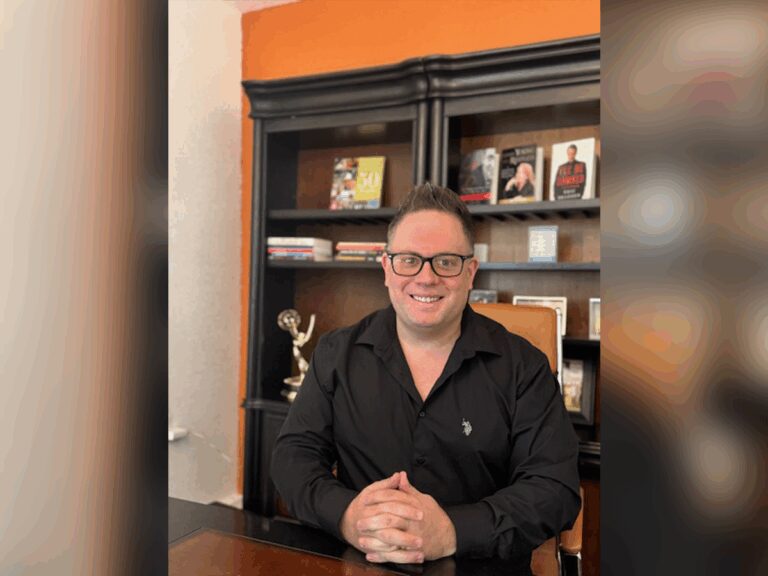 Gregory Slamon sitting at his desk next to an Emmy award and books.